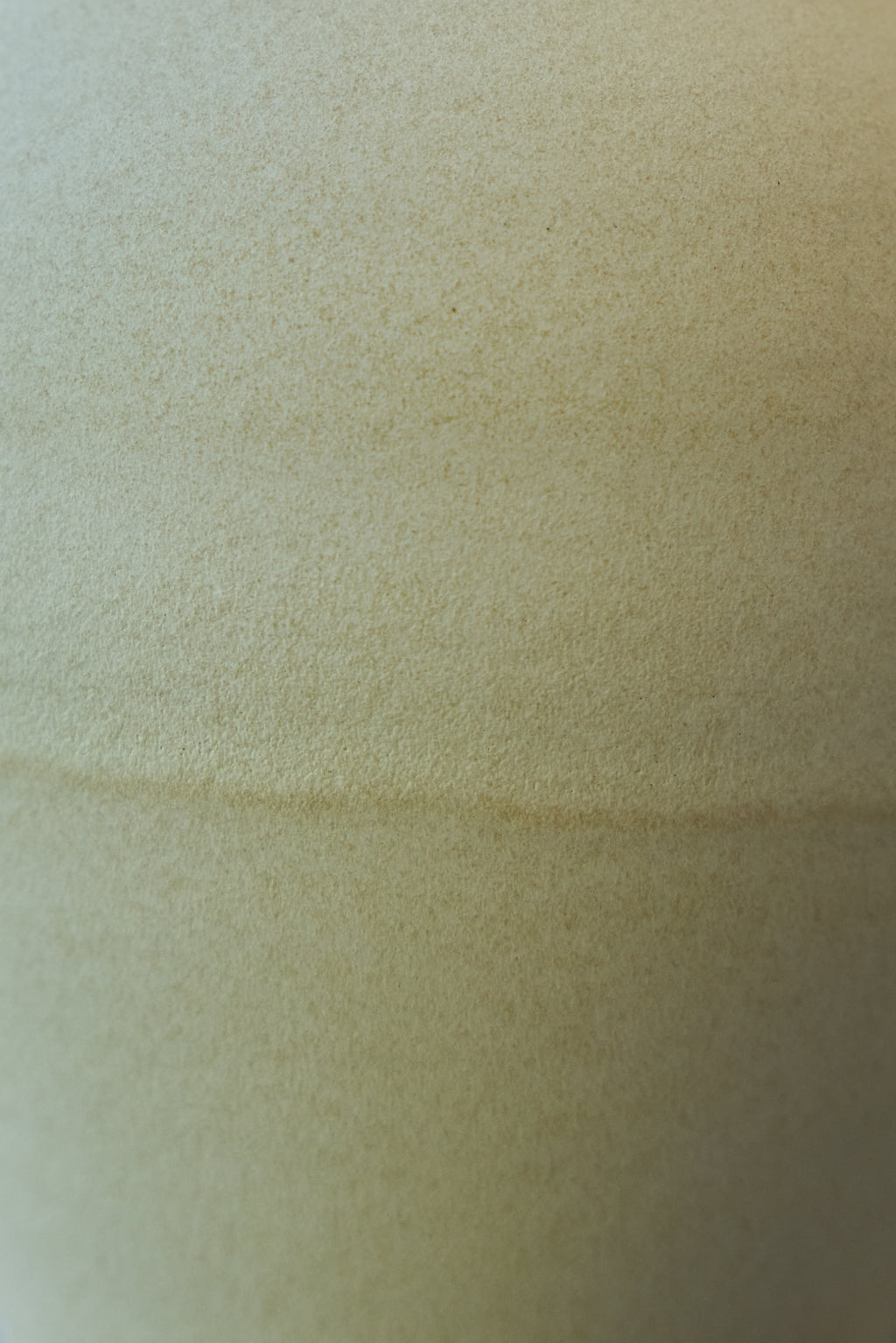 A close-up of a textured off-white glazed porcelain surface with a subtle horizontal overlap.