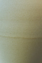 A close-up of a textured off-white glazed porcelain surface with a subtle horizontal overlap.