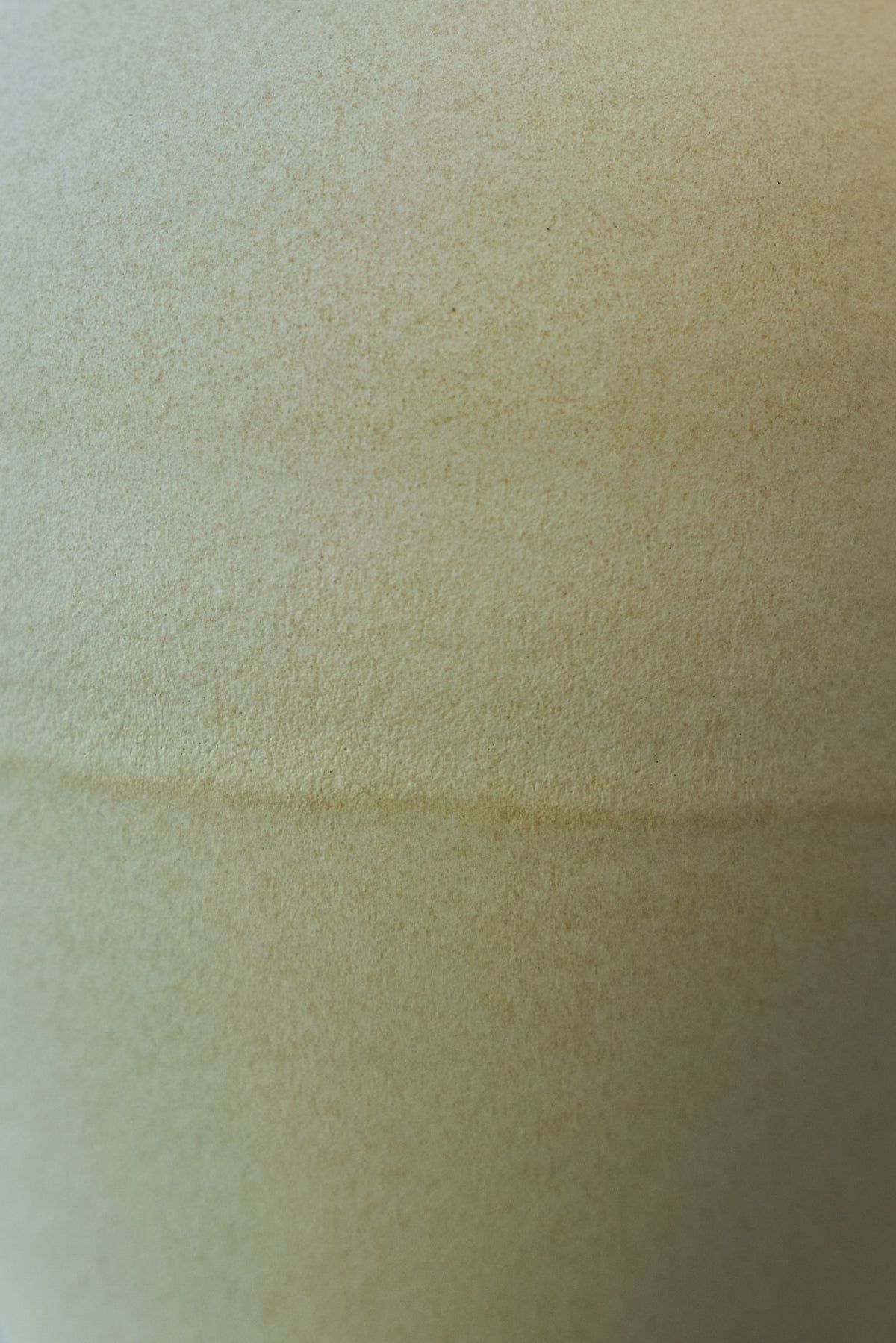 A close-up of a textured off-white glazed porcelain surface with a subtle horizontal overlap.